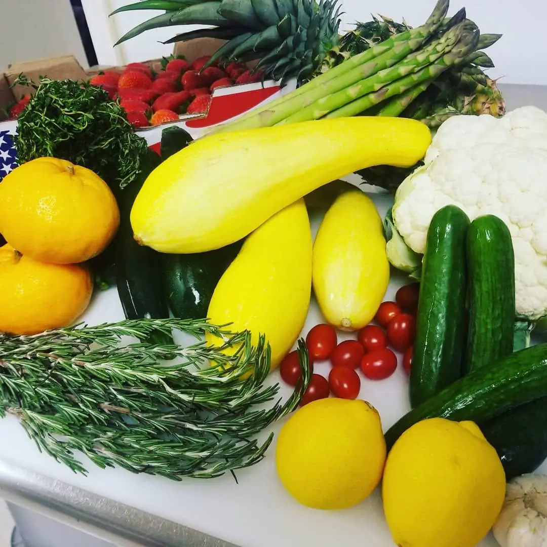 Fresh squash, cucumbers, cauliflower, citrus, and herbs staged for prep