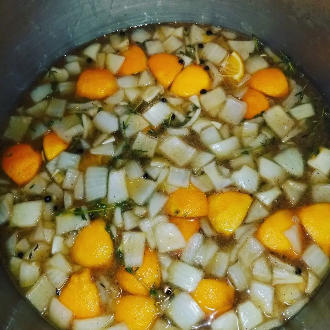 Onions, citrus, and herbs prepped in a stockpot for a Huck's brine